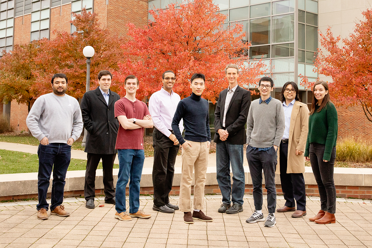 A group photo of the researchers standing together outdoors on the UIUC campus with trees and a building behind them. 