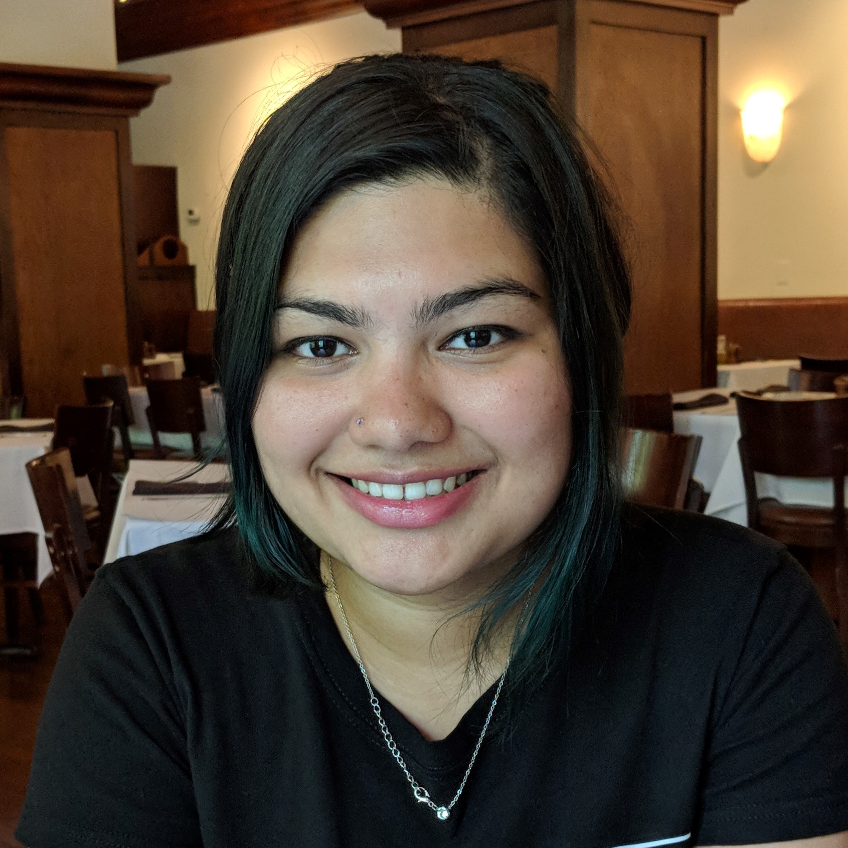 Portrait image of Remshi Dani sitting in an empty restaurant.  