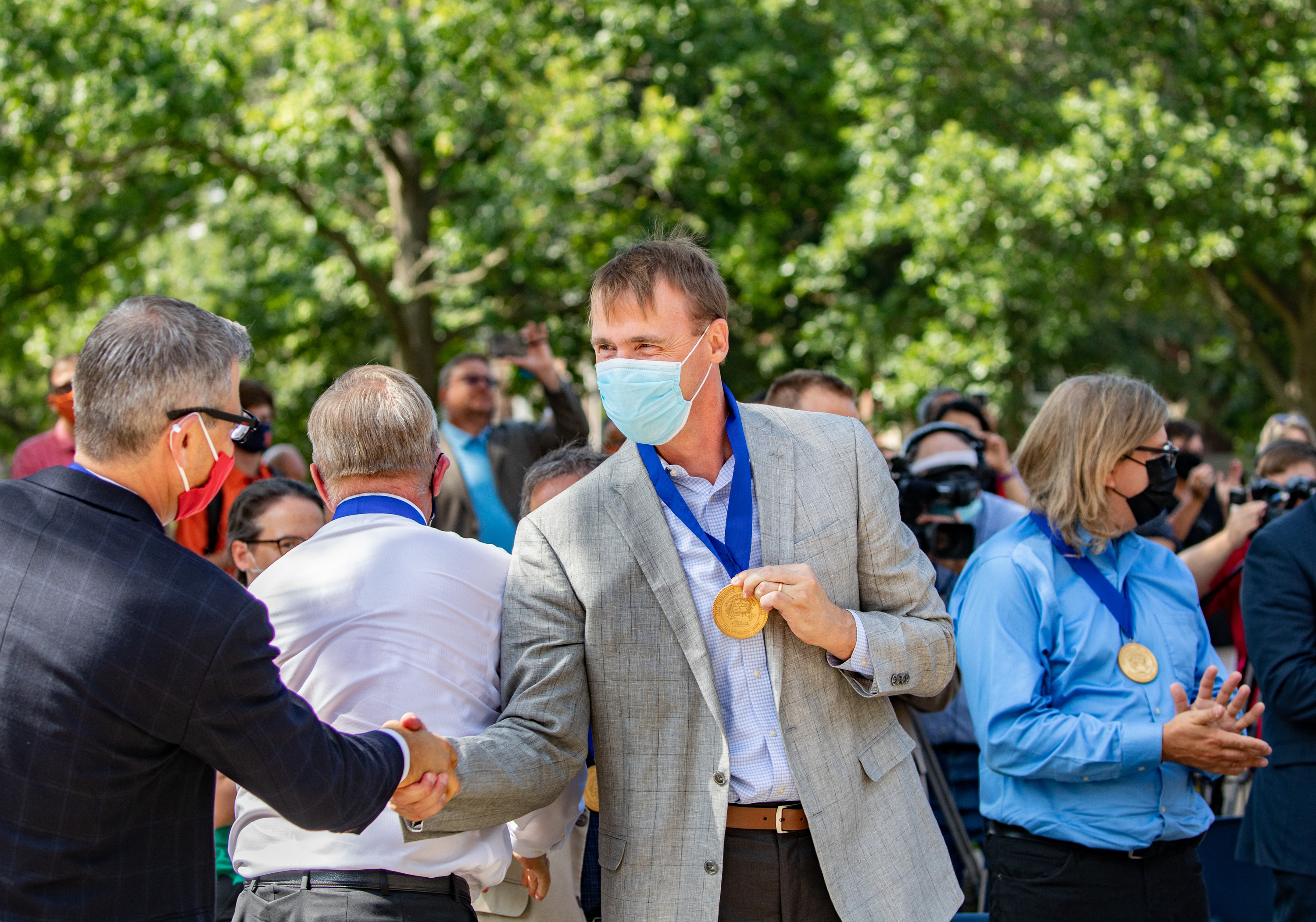 Martin Burke shakes hands with Paul Hergenrother after presentation of the Presidential Medallions during the ceremony on the UIUC campus on the quad.