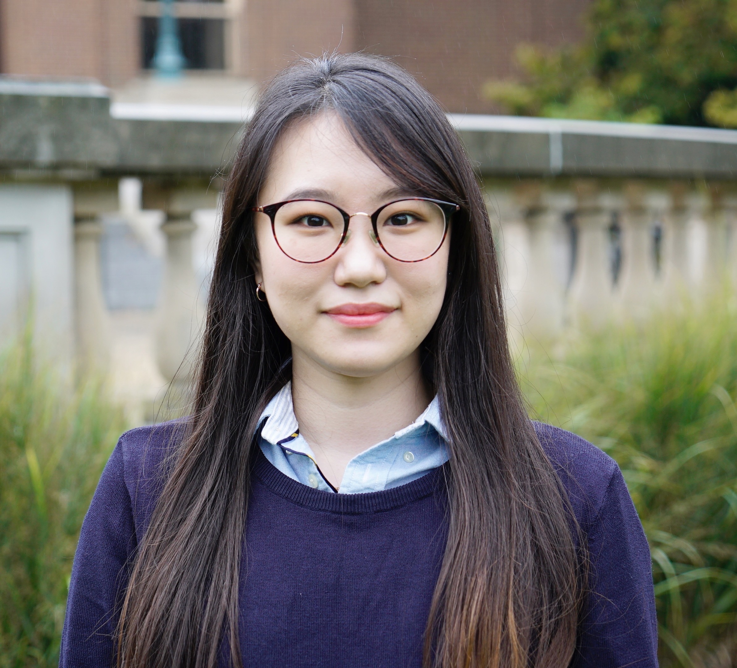 Portrait of Hanah Na standing in front of a tall grass and a pond.