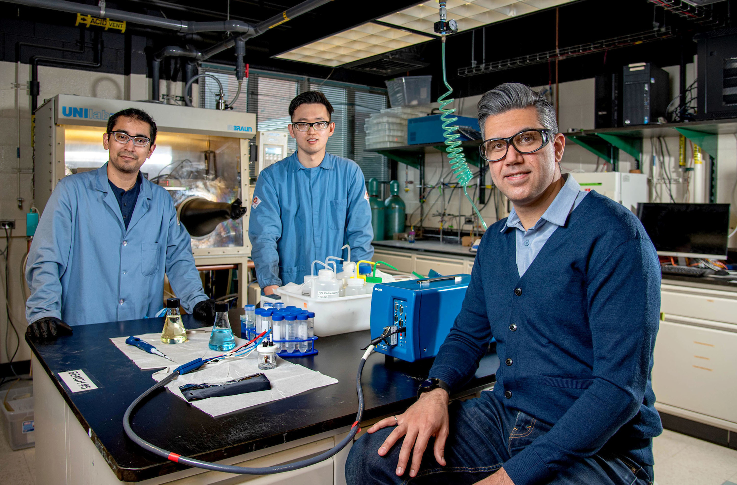 Three researchers sit around a table in Materials Research Lab.