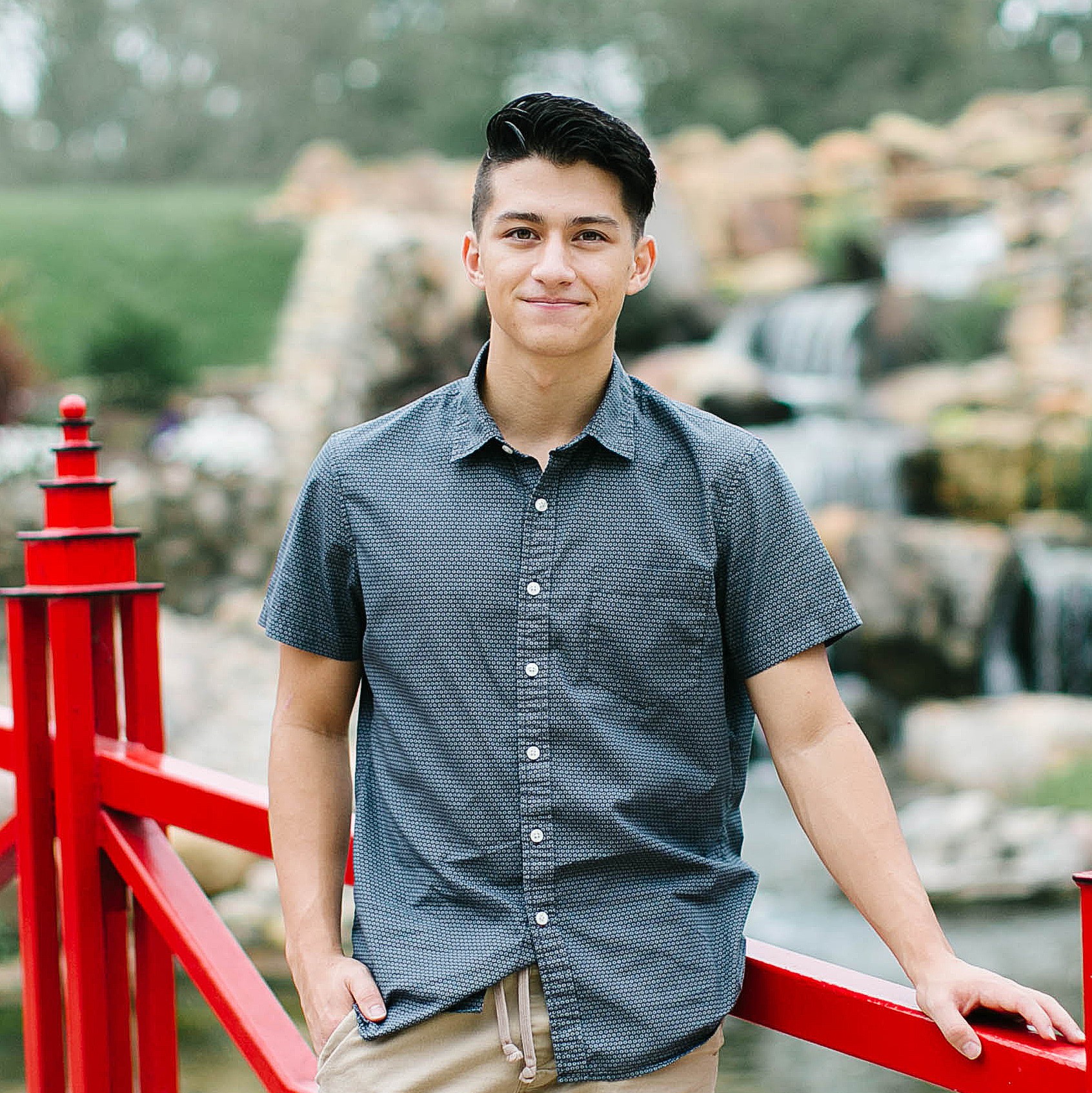 Curt Althaus standing on a red bridge with a rock waterfall in background