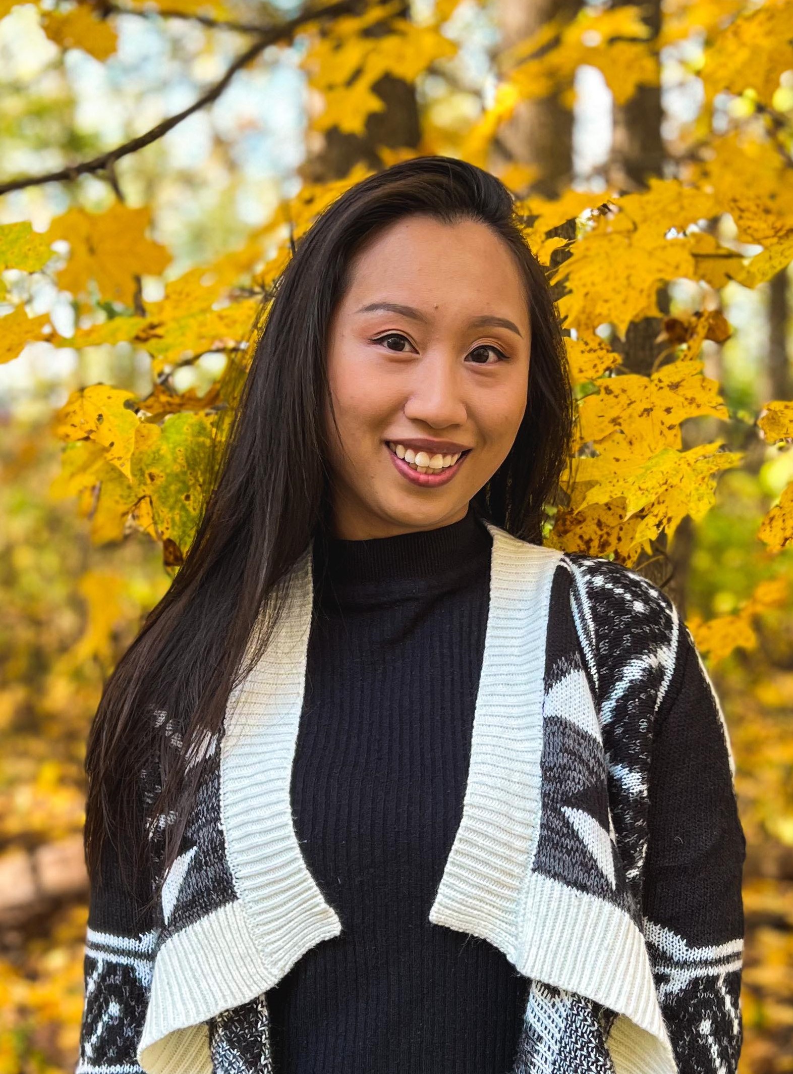 Portrait of Anita Wo standing outdoors in front of trees showing fall colors