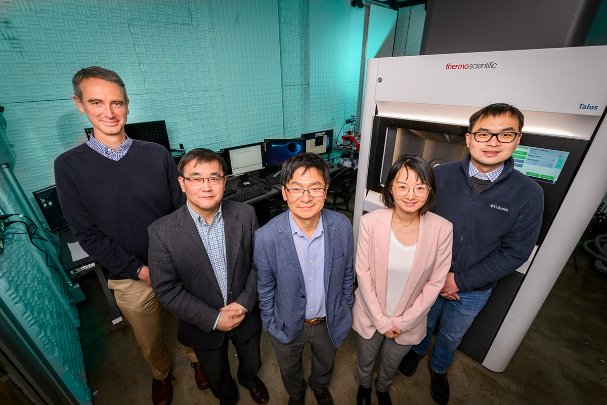 Researchers stand side by side in a lab looking up into the camera lens