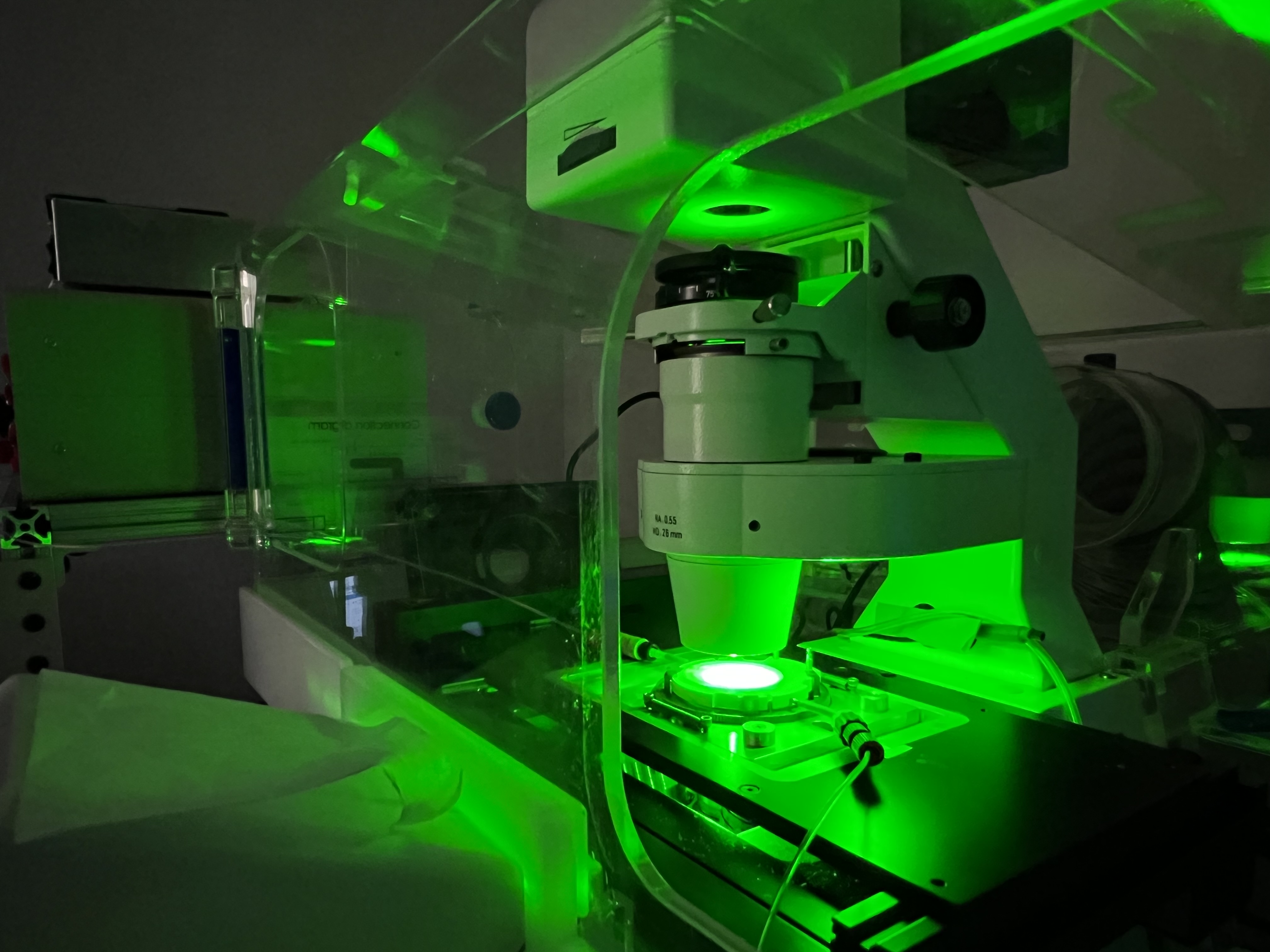 A customized microscope in the Han lab emits green light while operating.