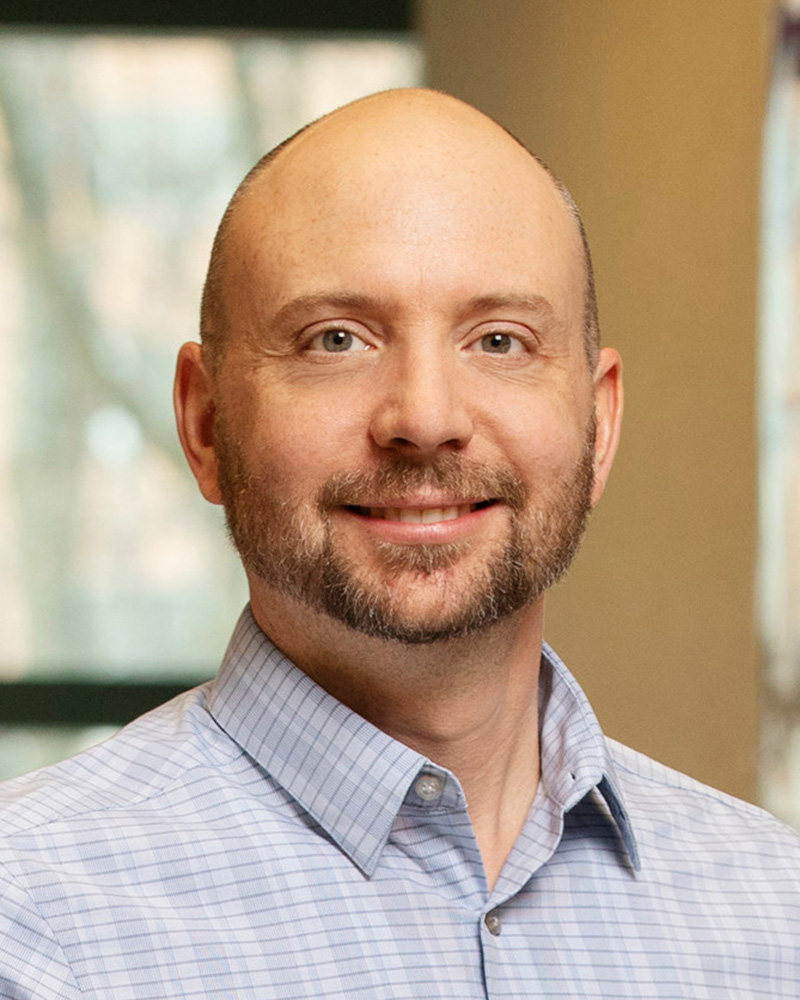 Head shot of Charles Schroeder with a window/wall in background