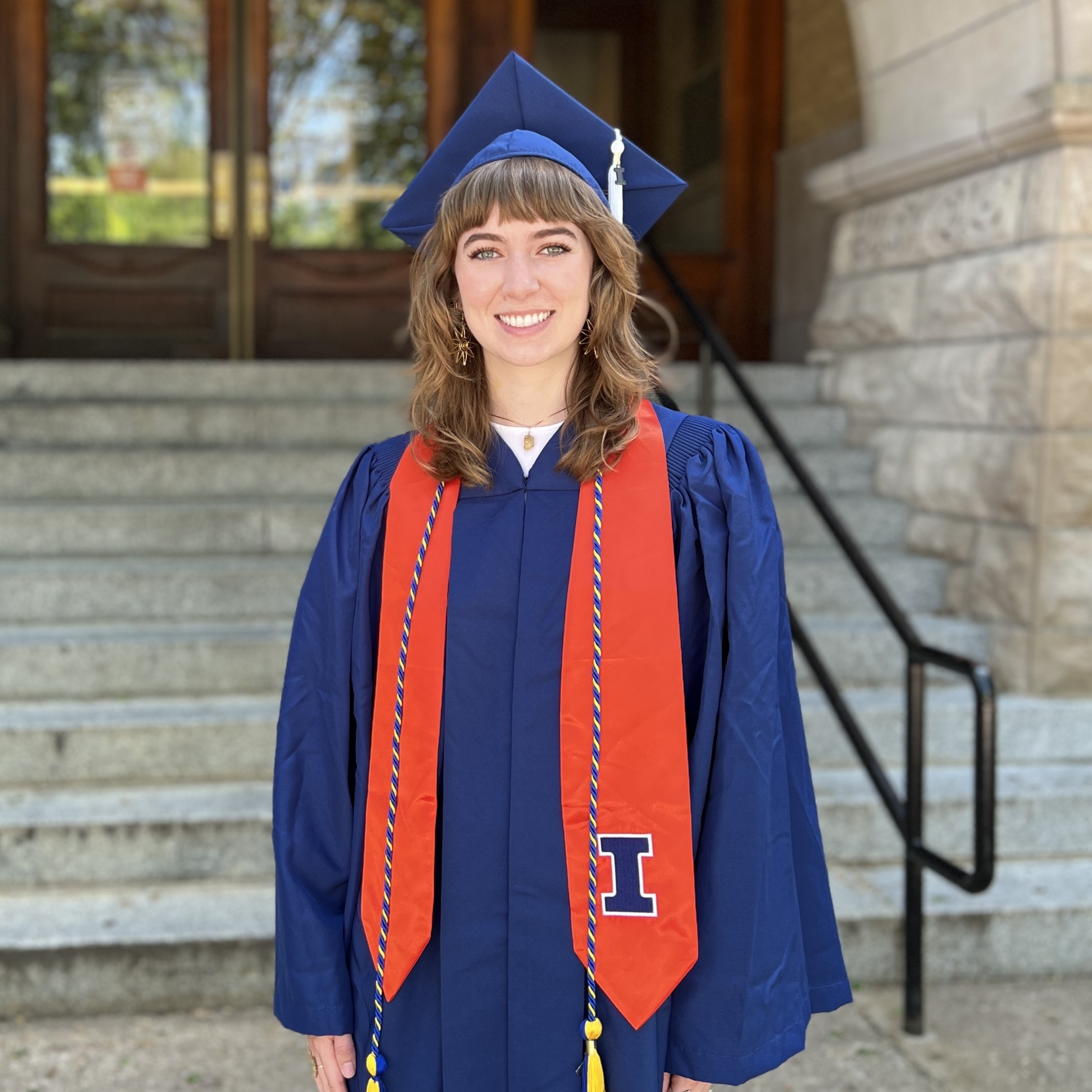 Portrait of Megan Murphy in cap and gown in front of Noyes entrance