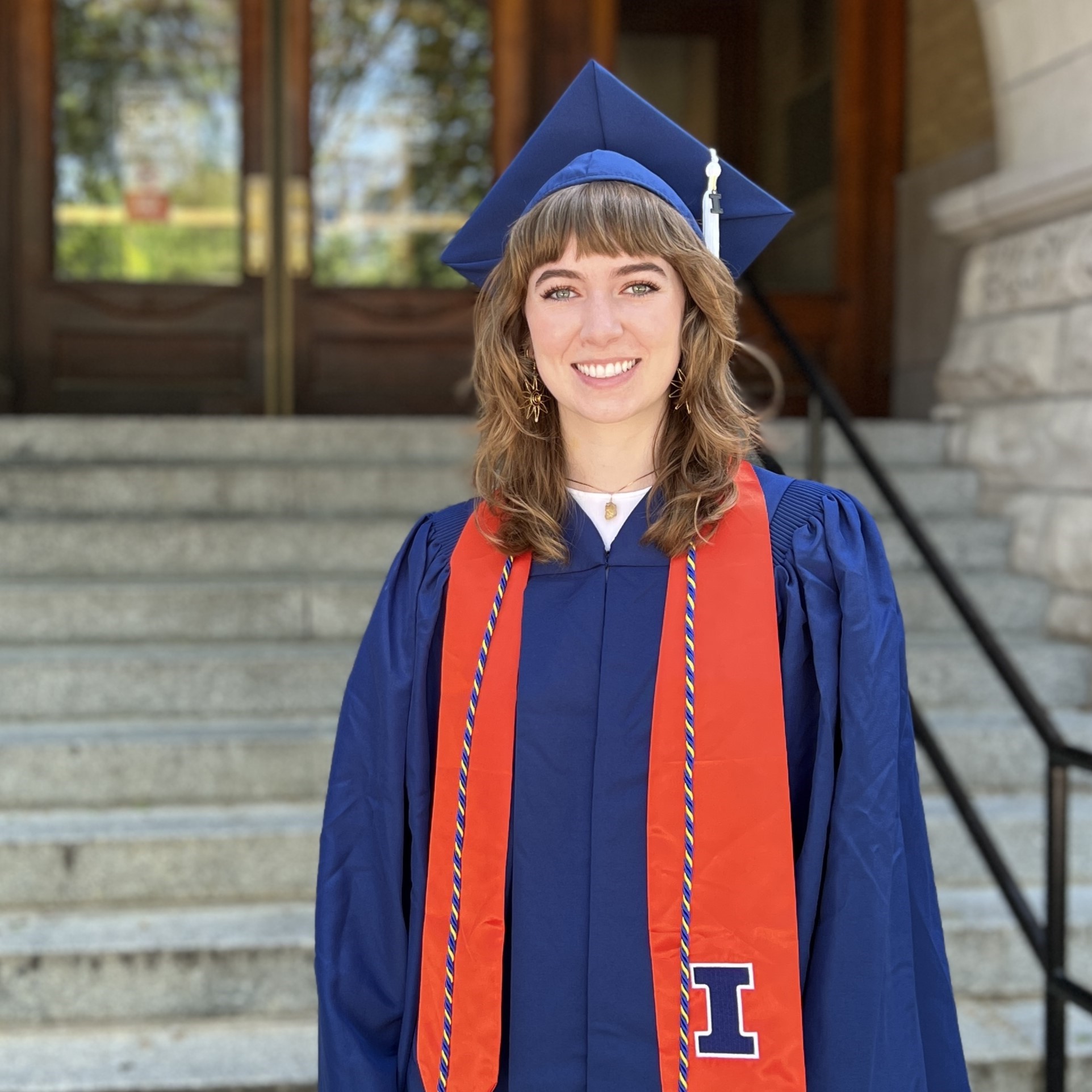 Megan Murphy in cap and gown in front of Noyes entrance