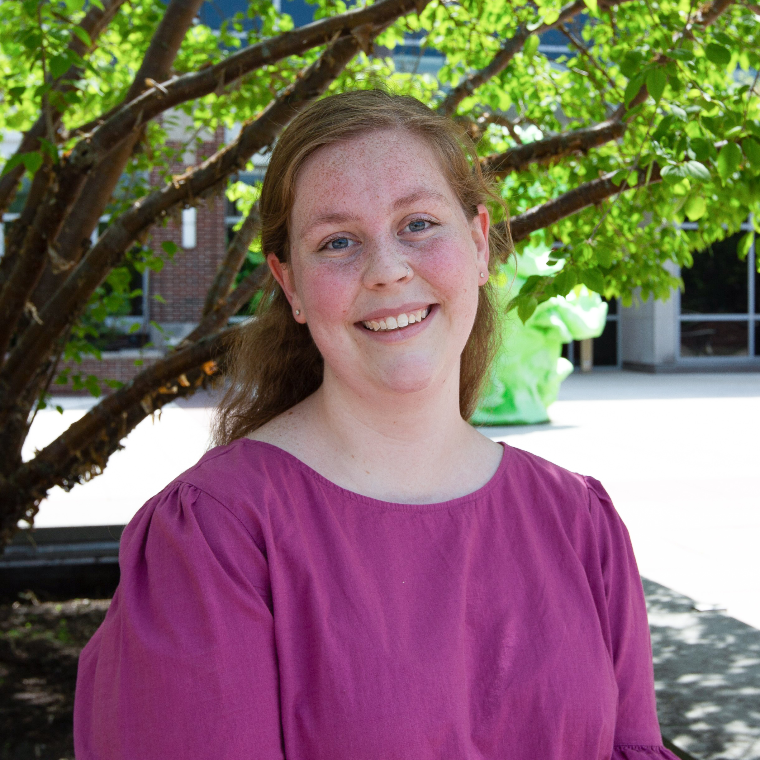 Portrait of Rebecca Ulrich sitting outdoors under a tree