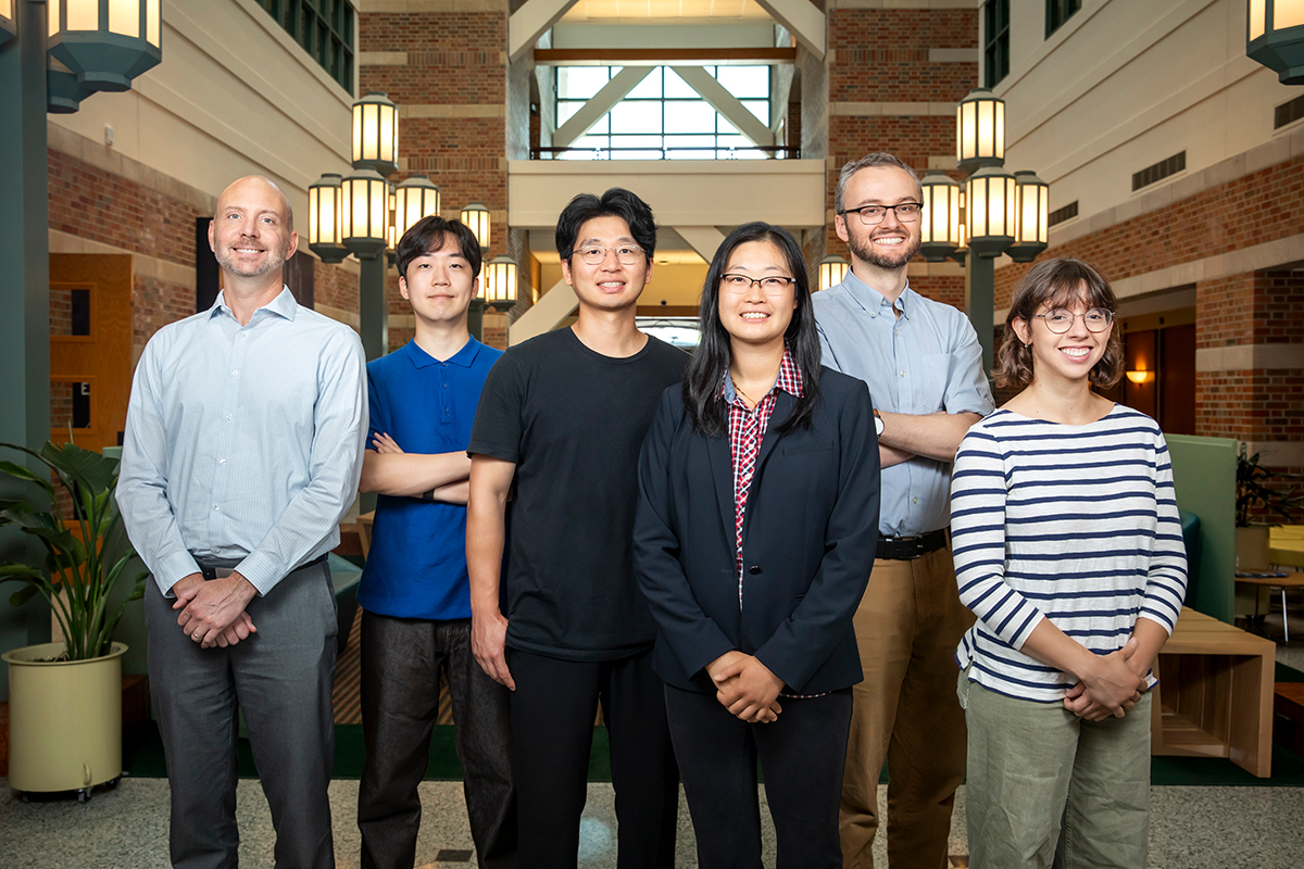 Group of six researchers stand side by side in the atrium of the Beckman Institute on the Illinois campus