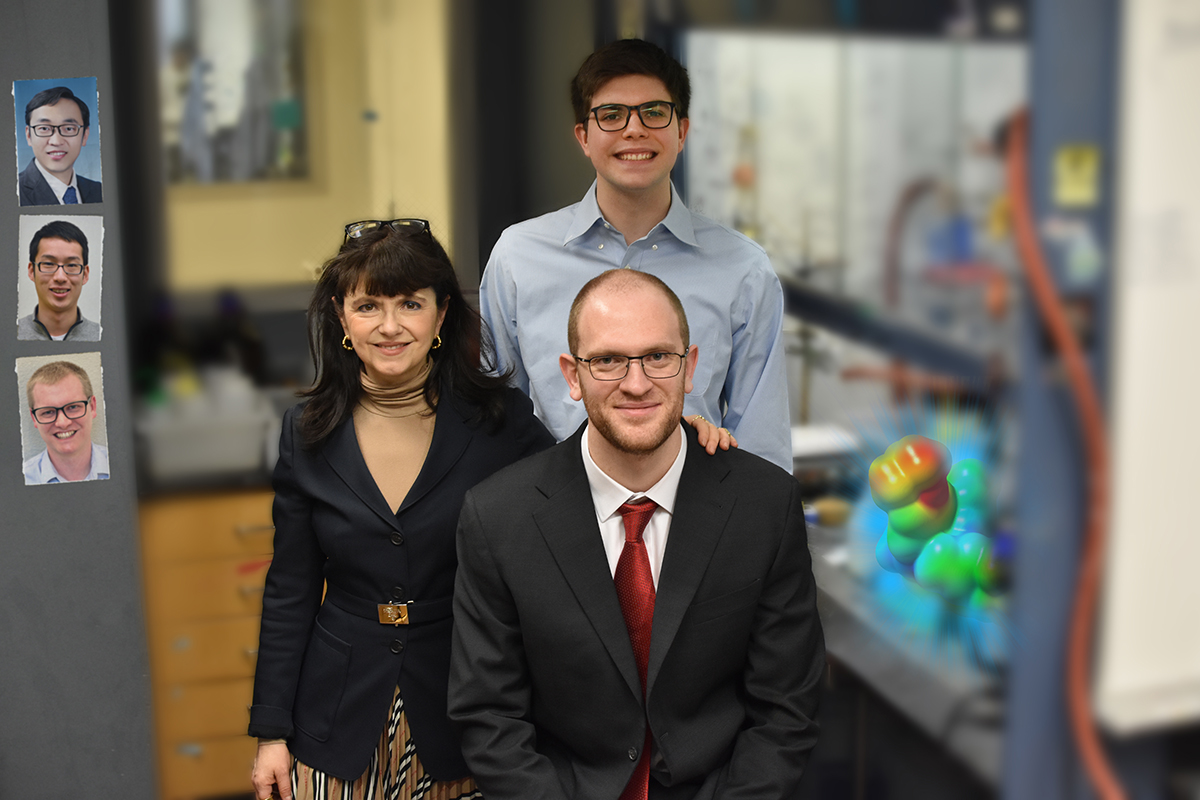 Three researchers stand side by side near equipment in a chemistry lab.