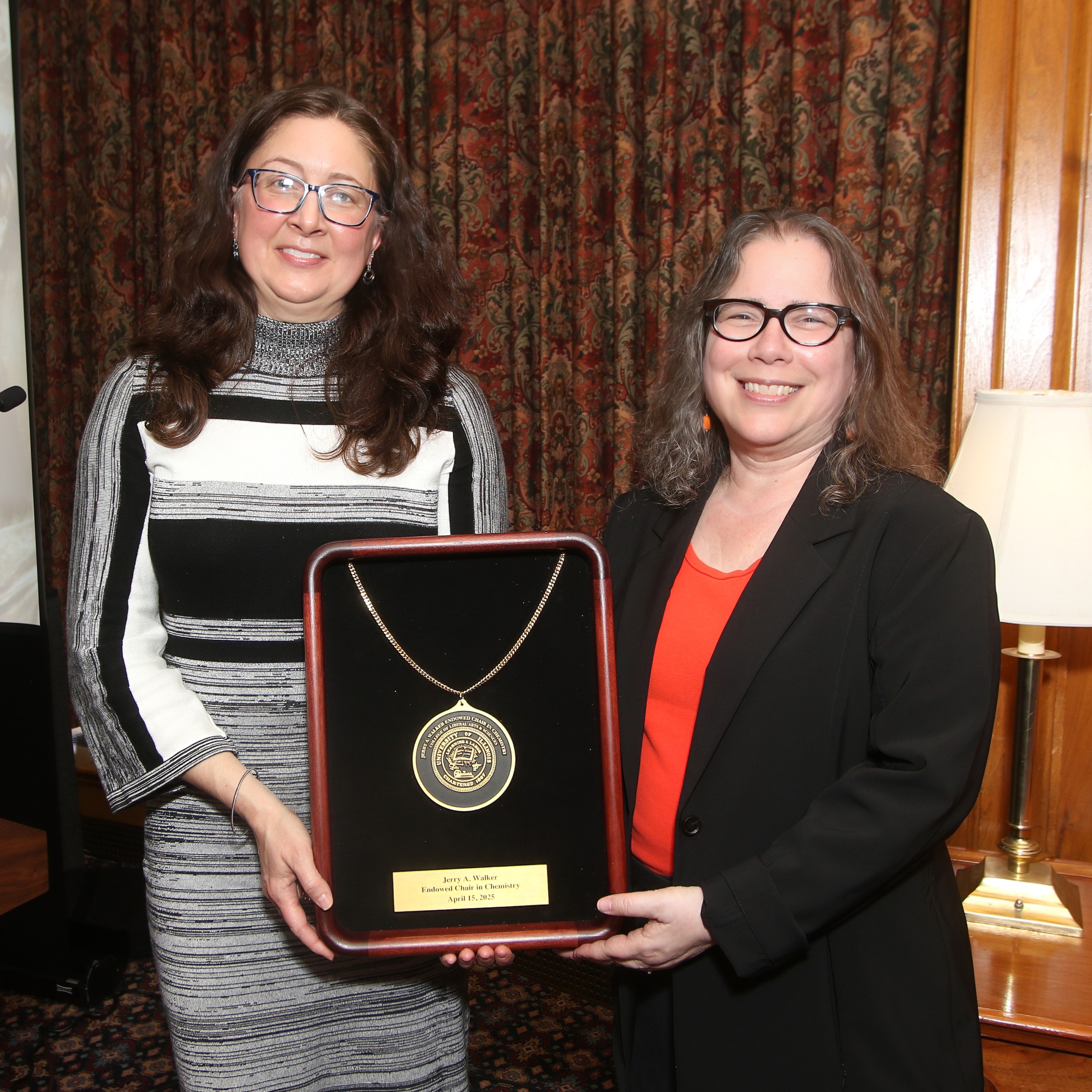Two people standing together holding a shadow box with a medal inside
