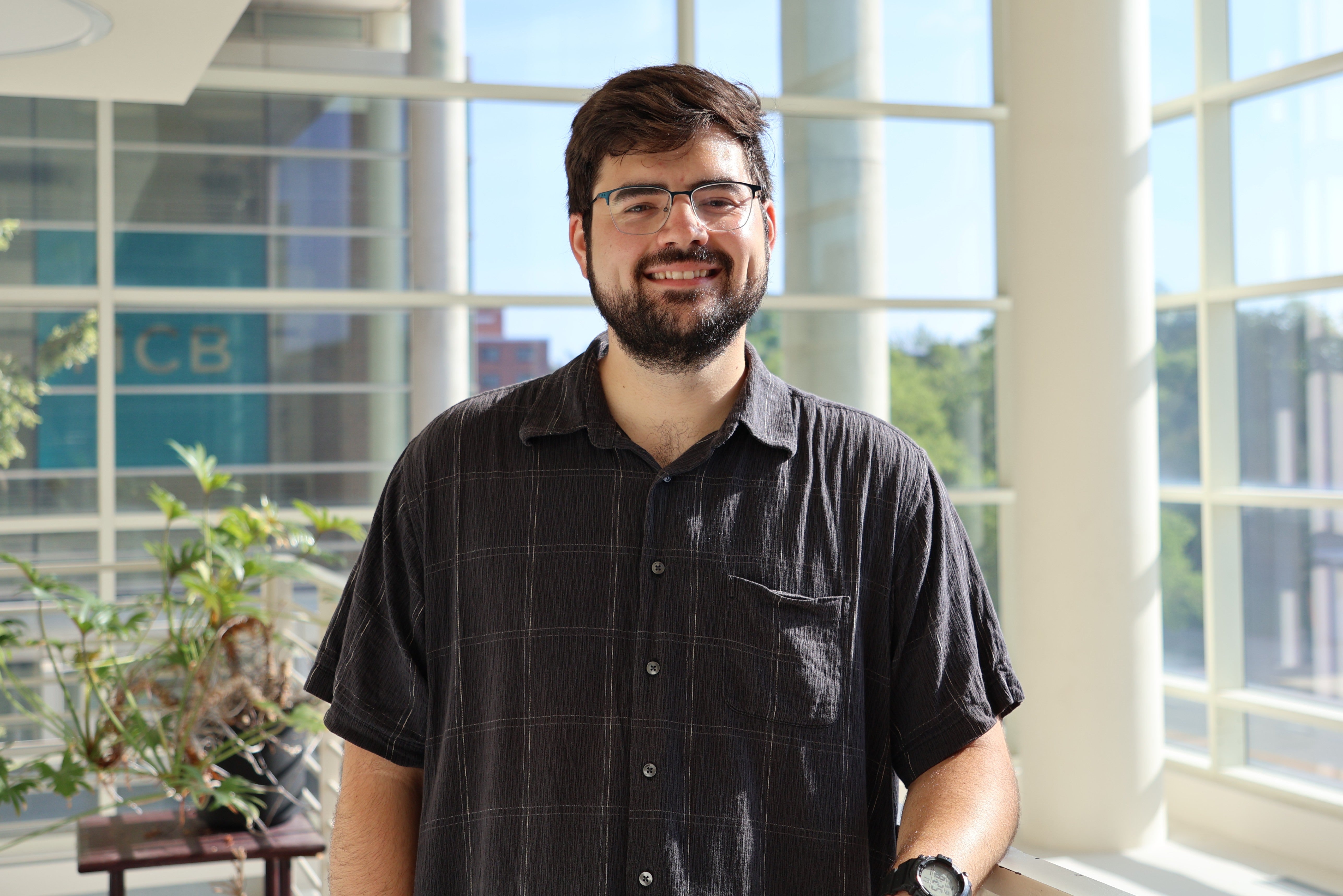Portrait of Noah Haskin standing on a balcony in a glass walled lobby