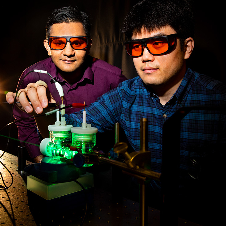 Prashant Jain and Sungju Yu performing artificial photosynthesis experiments using green light. Photo by Fred Zwicky