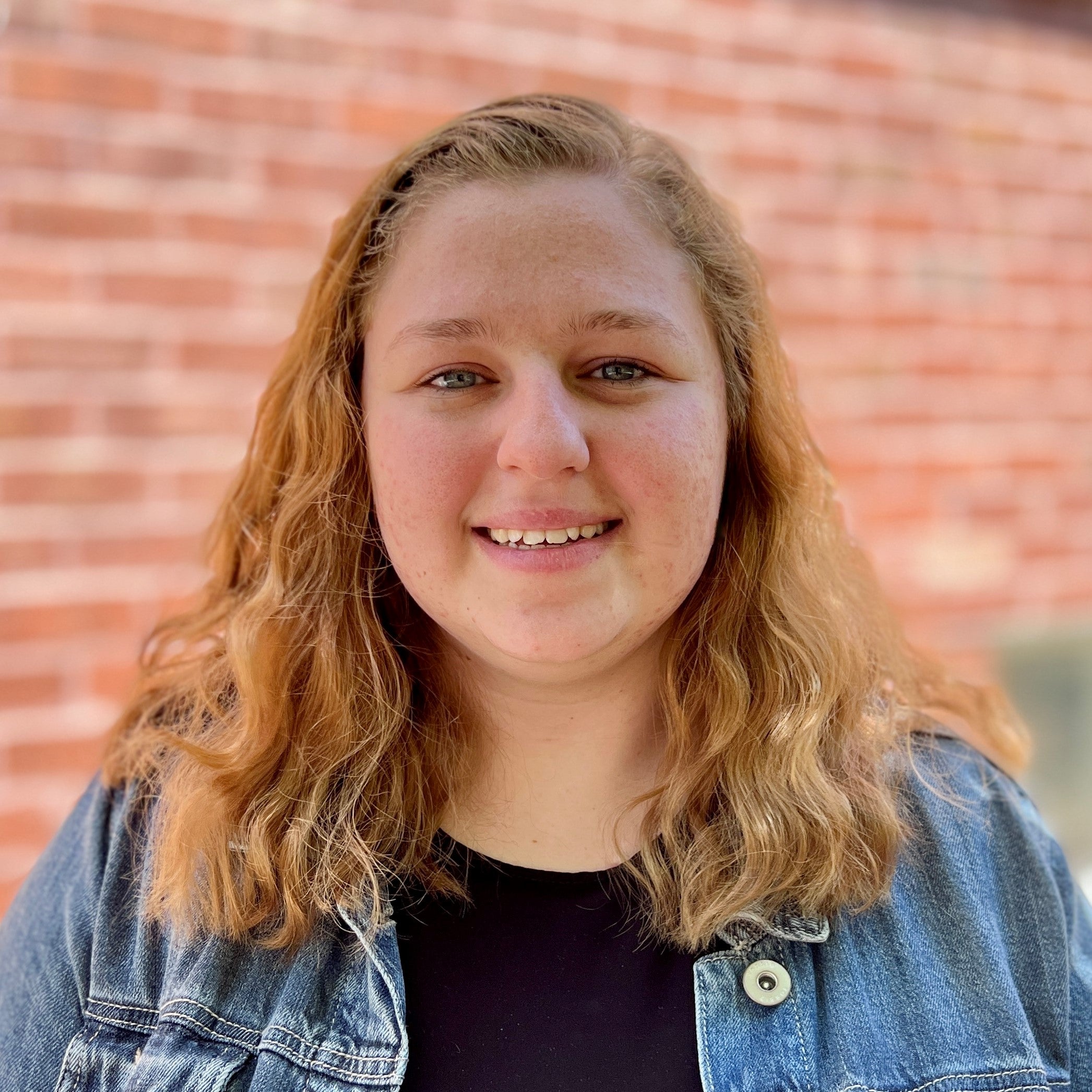 Head shot of Mackenzie Murray on a brick wall background