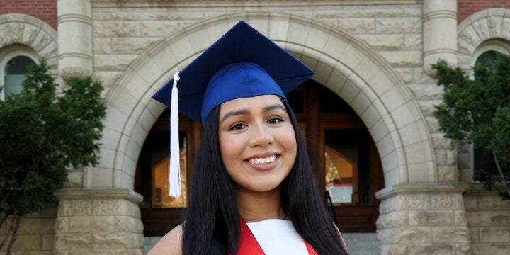Abbigail Calixto in a graduation cap in front of an arched entrance