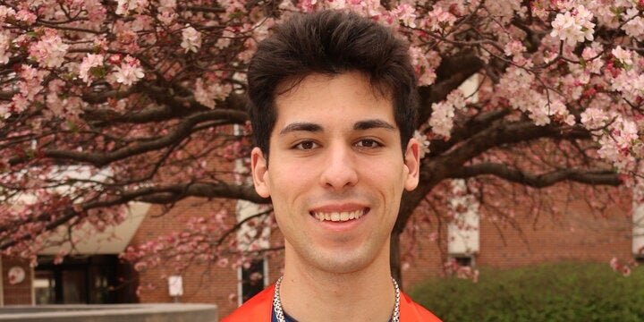 Vito Failla in a graduation gown in front of a tree
