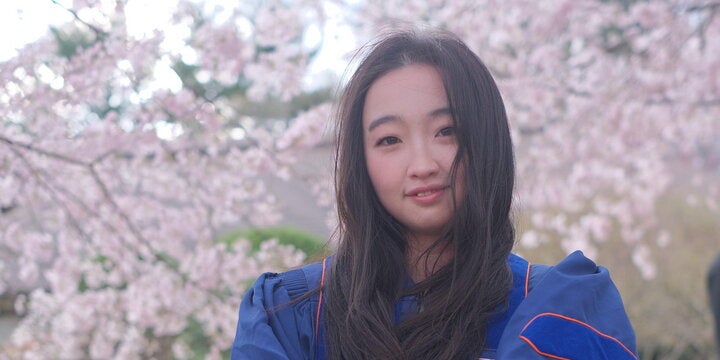 Head shot of Yanqi Tan in front of blooming trees