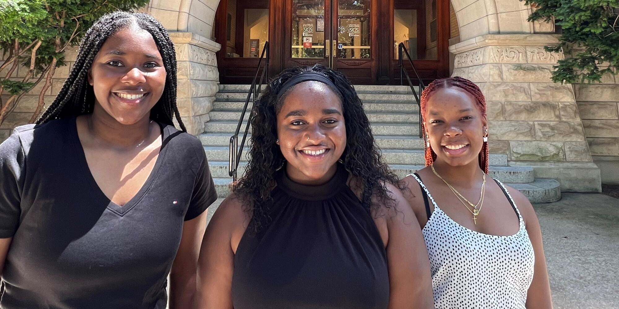 Three summer research scholars pose in front of West entrance to Noyes Laboratory.