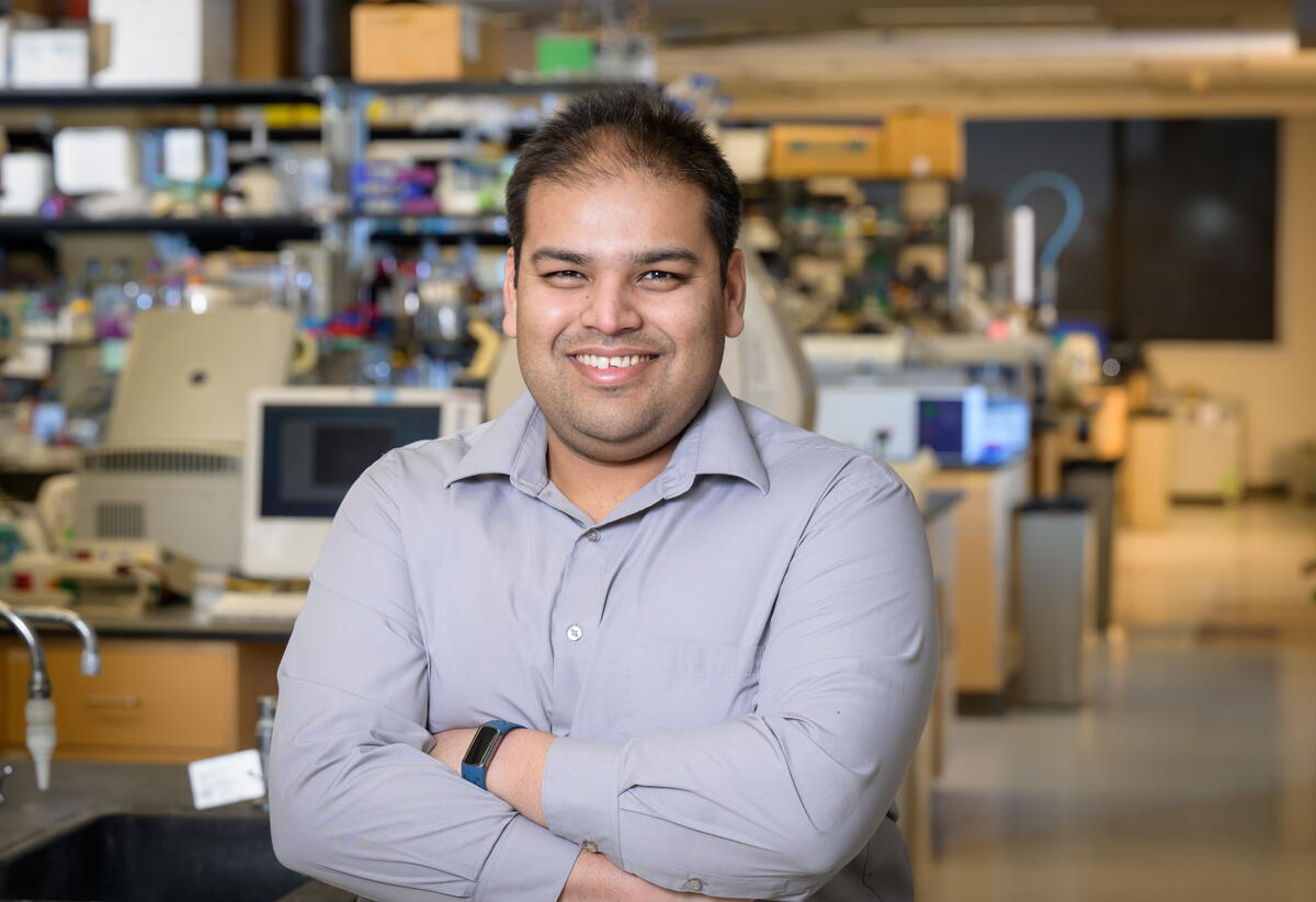 Angad Mehta standing in a lab with arms crossed in front of him