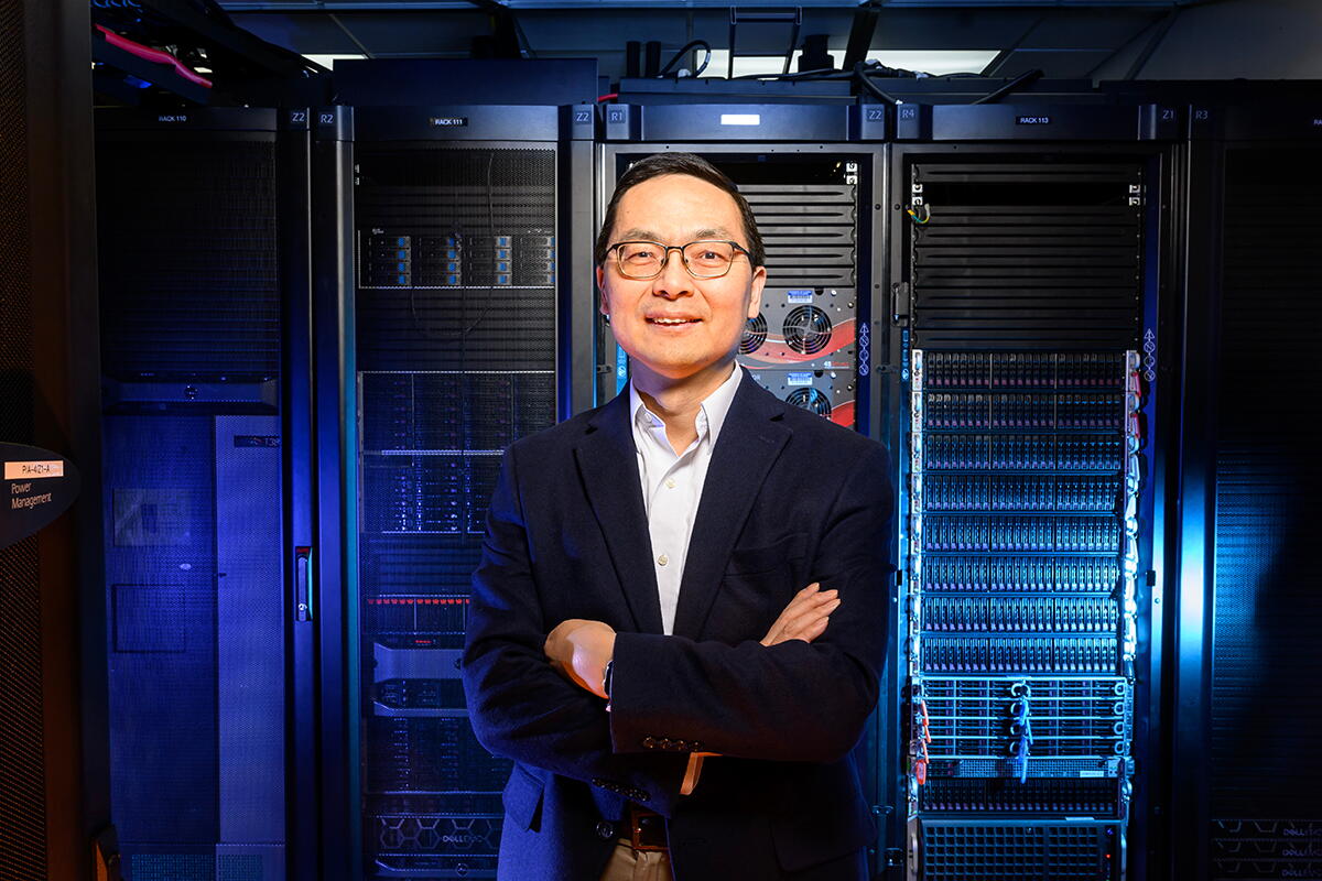 Huimin Zhao standing with arms crossed in front of a large bank of computer data equipment