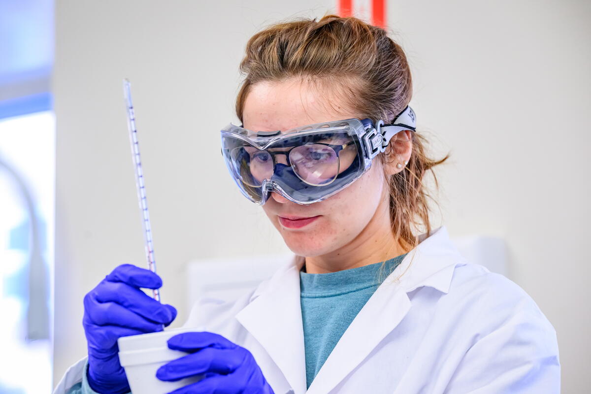 Student in a lab with goggles, gloves and lab coat