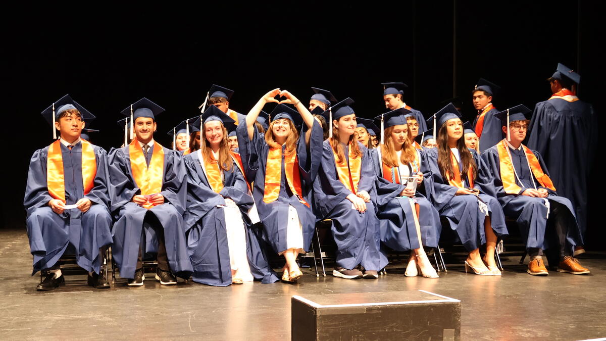 Group of graduates in graduation regalia sitting on stage