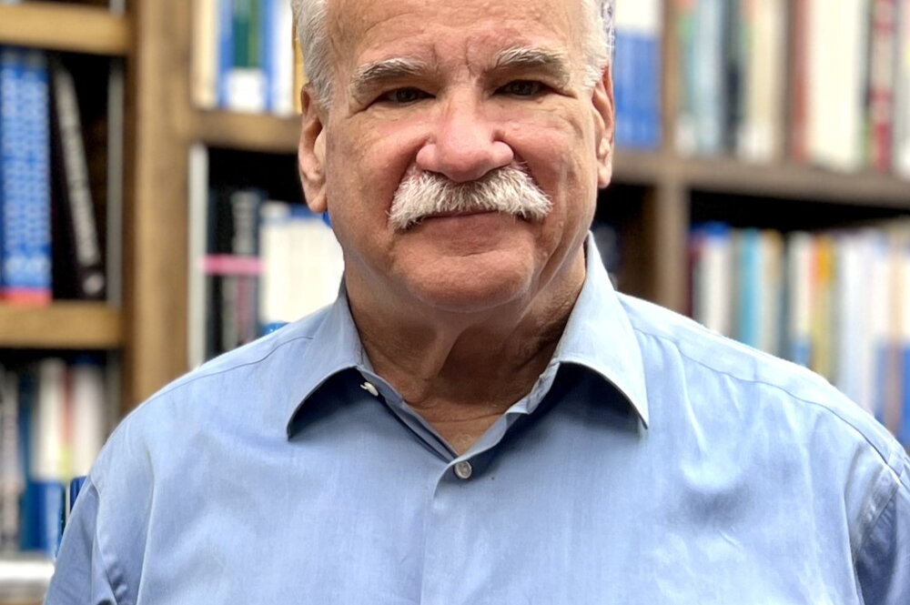 Head shot of Scott Denmark in front of a wall of books on a bookshelf