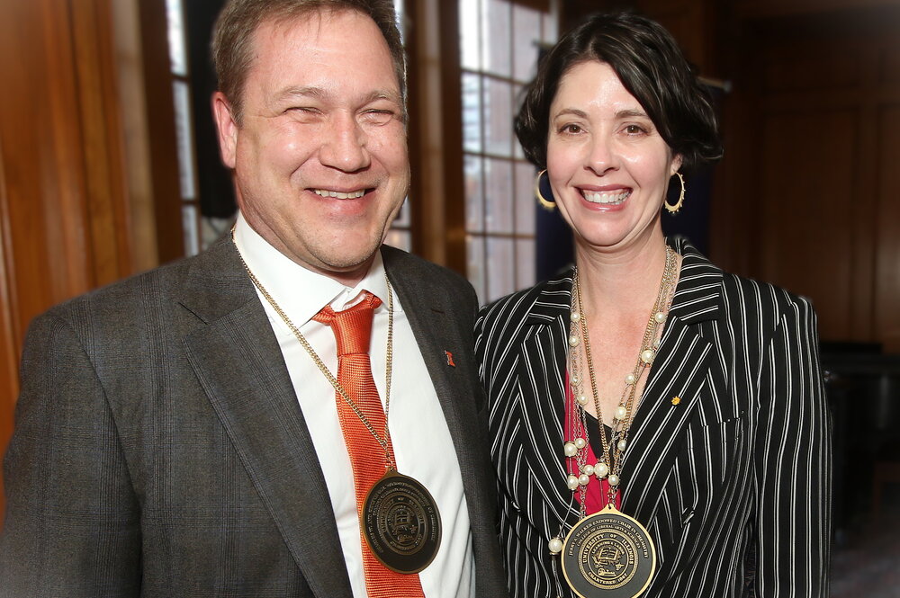 Two people standing side by side with medals around their necks