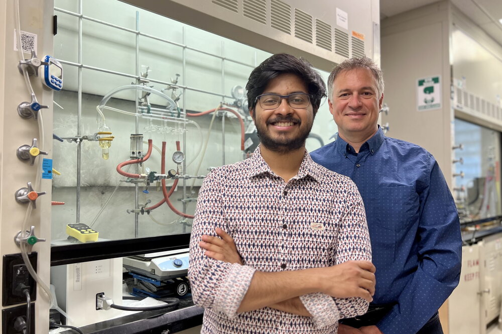 Shounak Nath and Liviu Mirica stand together in front equipment in a chemistry lab