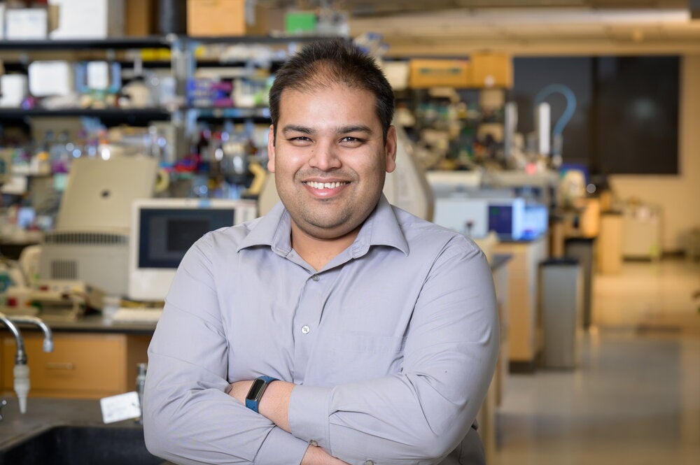 Angad Mehta standing in a lab with arms crossed in front of him