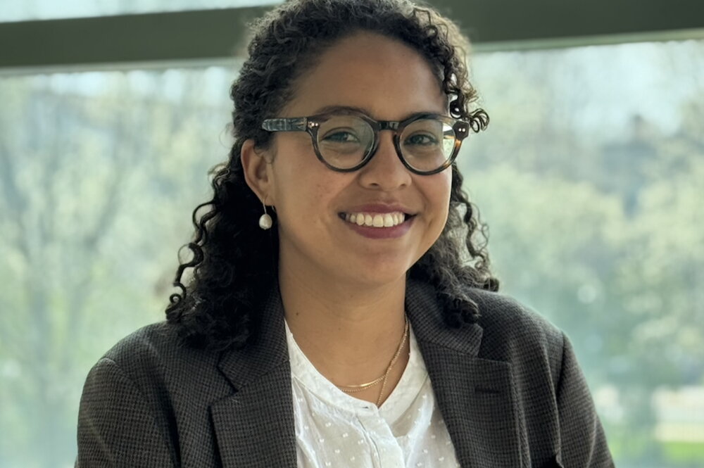 Head shot of Viviana Palacio-Betancur standing in front of a wall of glass windows