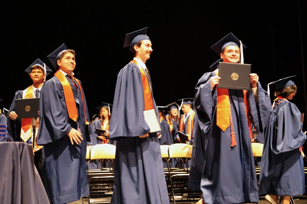 Graduates walking on stage in graduation regalia