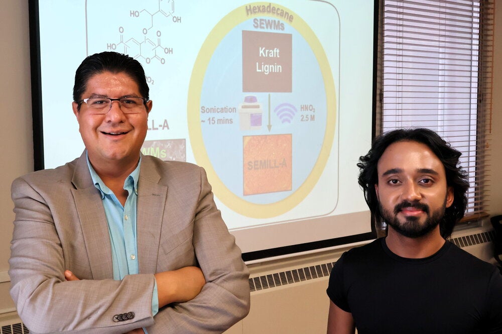 Joaquin Rodriguez-Lopez and Riyo Das standing in front of an overhead screen.