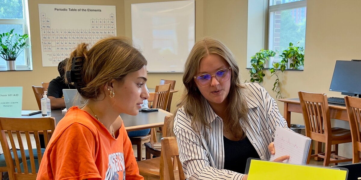 Two people sitting at a table going over chemistry 