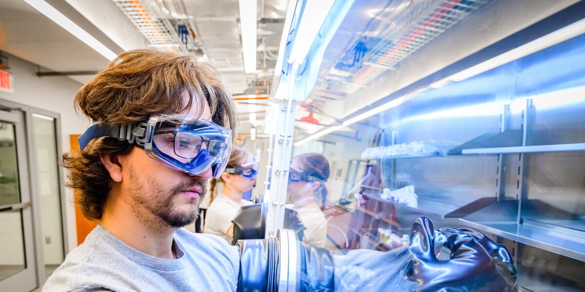 Student wearing goggles using a glovebox in a lab