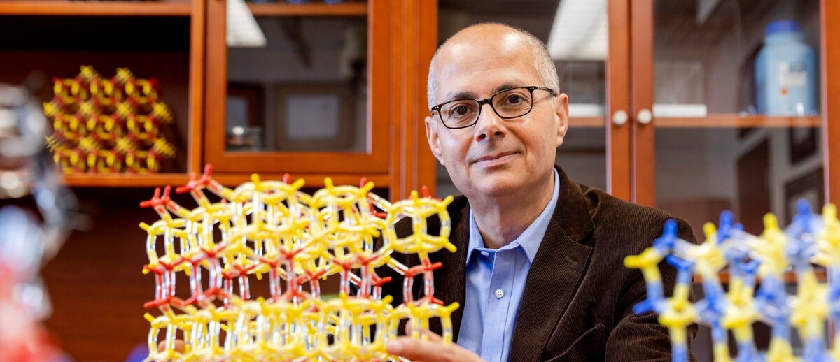 Omar Yaghi sitting at desk surrounded by molecular structures
