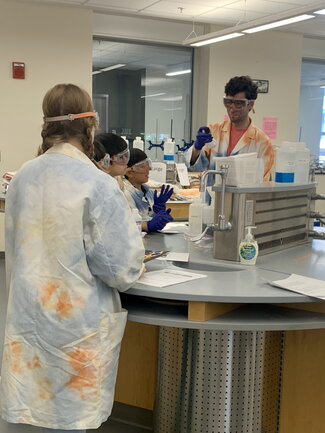 camp leader and kids in the lab doing chemistry experiment
