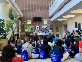 students sitting on floor watching a chemistry demonstration