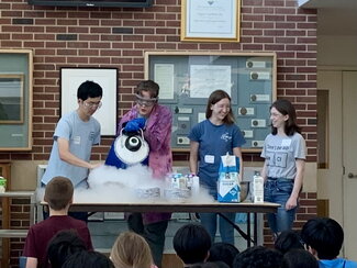 four adults behind a table doing a chemistry demonstration