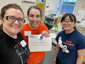 three people standing holding a paper with alphabet letters