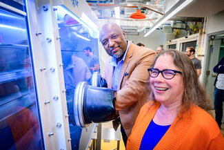 Two people standing in front of a chemistry glove box