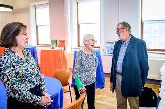 Three people stand together talking at a reception.