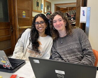 Two student volunteers sitting side by side at table 