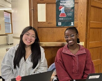 Two student volunteers sitting side by side at table 