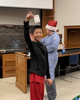 A boy holding a #4 playing card above his head so the audience can see the card