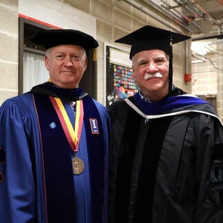 Two people in graduation regalia standing together