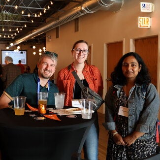 Three people at a table looking at camera