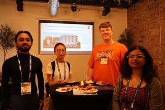 Four people standing together around a table with food and drinks