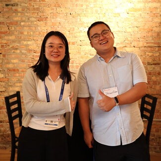 Two people standing together giving a thumbs up
